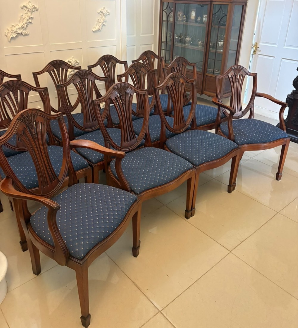 A set of twelve mahogany shield back dining chairs featuring carved backrest splats, square tapered legs, and blue patterned upholstered seats. View XIII