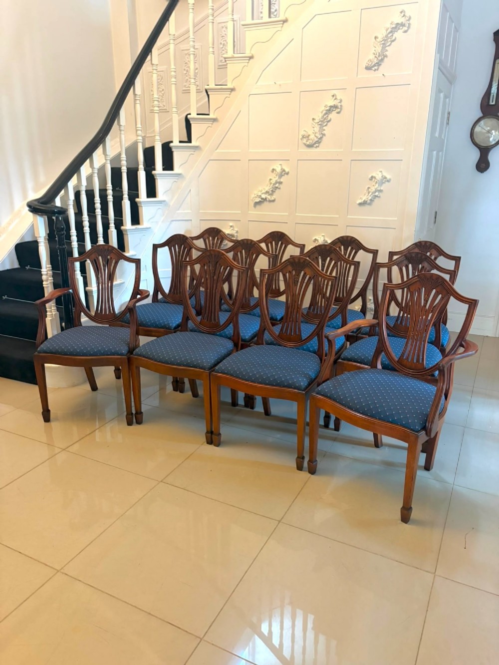 A set of twelve mahogany shield back dining chairs featuring carved backrest splats, square tapered legs, and blue patterned upholstered seats. View XIV