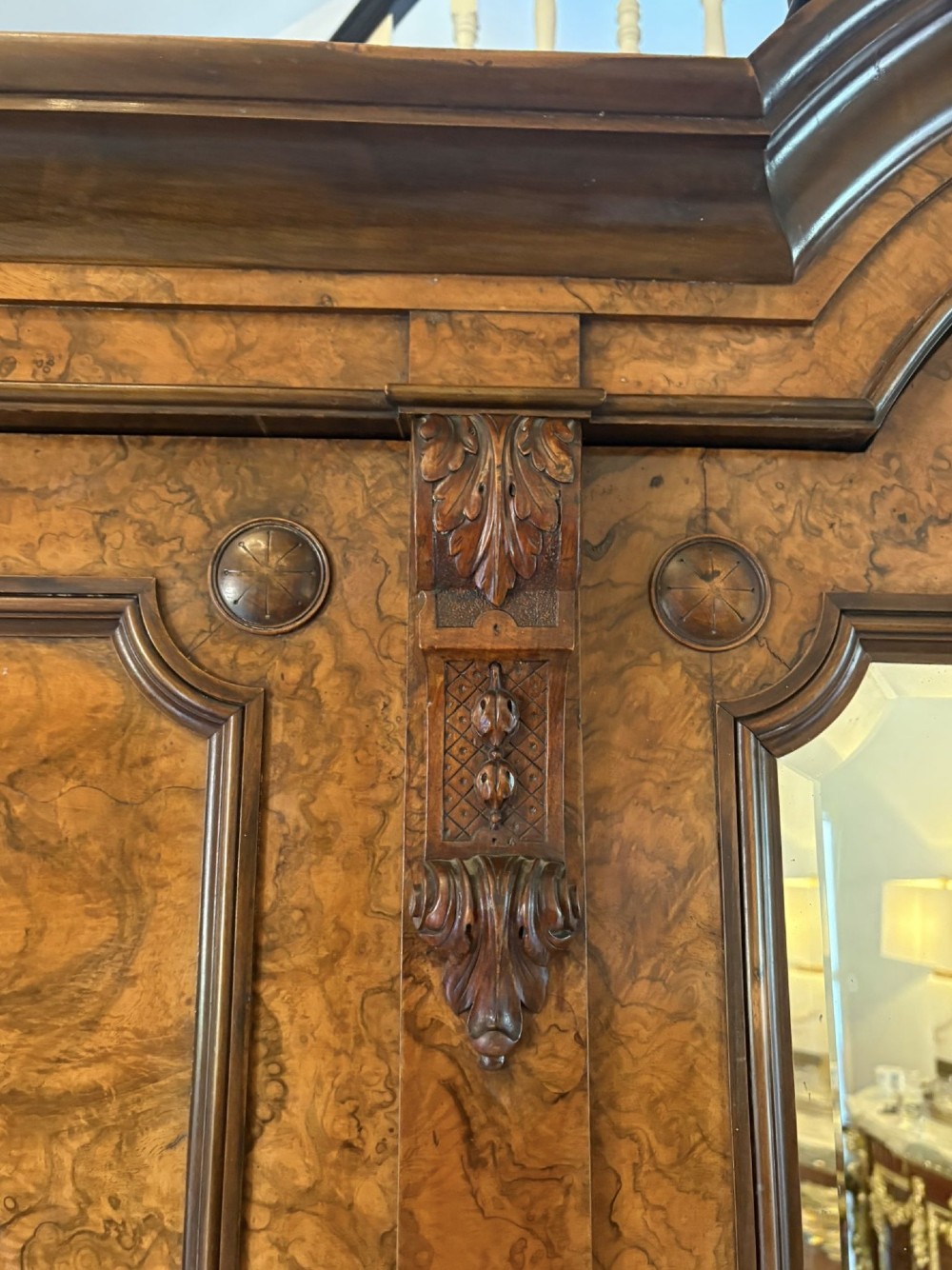 A large Victorian burr walnut three-door wardrobe with a central arched mirrored door, oval mirrors set into side panels, and carved pediment details. View VII