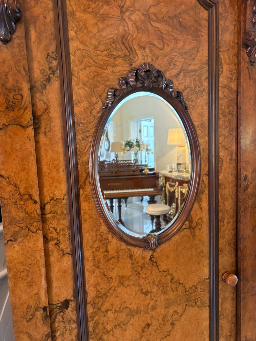 A large Victorian burr walnut three-door wardrobe with a central arched mirrored door, oval mirrors set into side panels, and carved pediment details. View IX