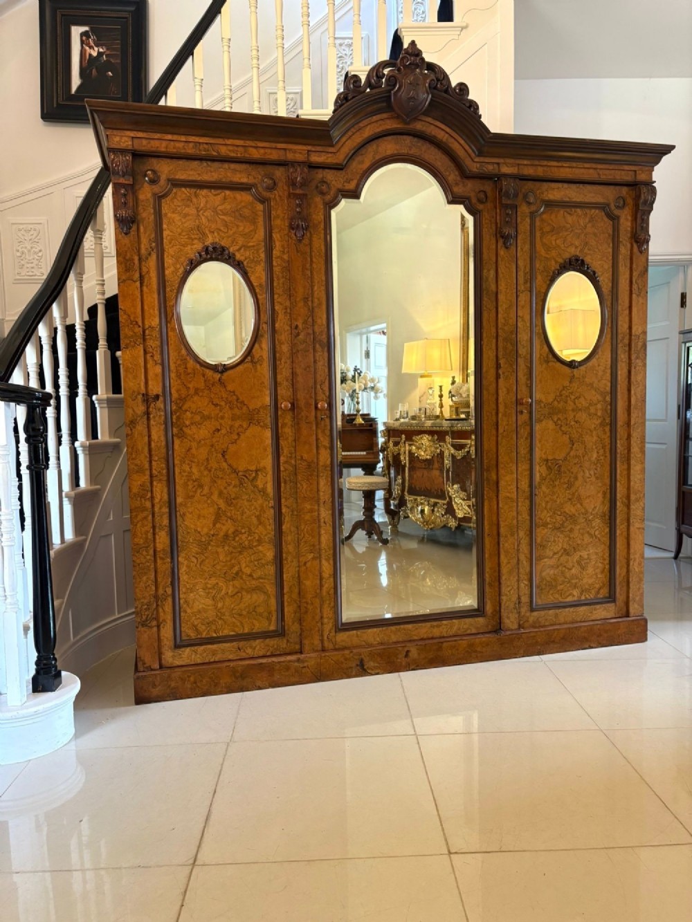 A large Victorian burr walnut three-door wardrobe with a central arched mirrored door, oval mirrors set into side panels, and carved pediment details. View XIII