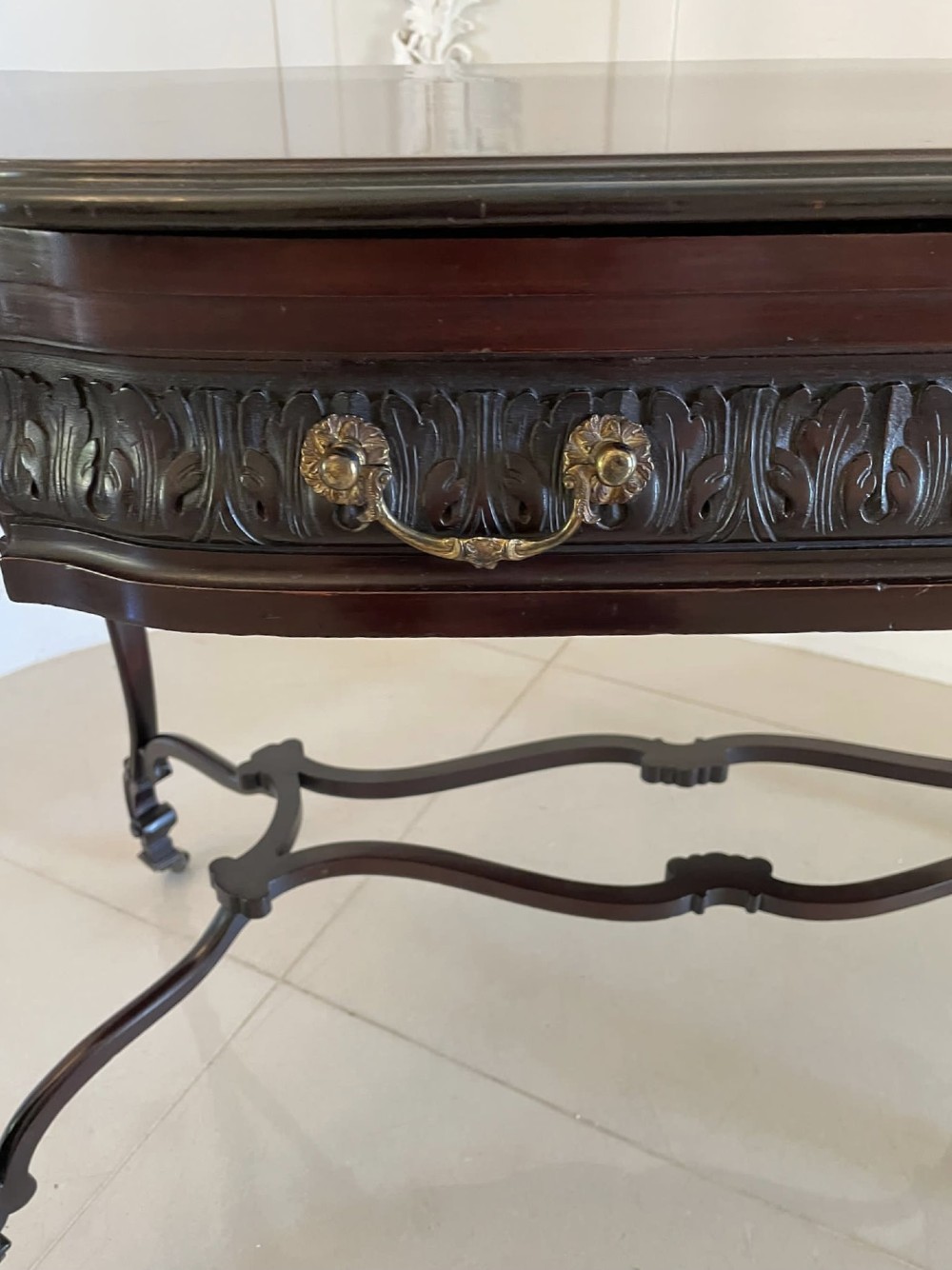 An antique Victorian dark mahogany centre table featuring a shaped serpentine top, carved frieze with brass handles, cabriole legs, and an arched scroll stretcher. View III