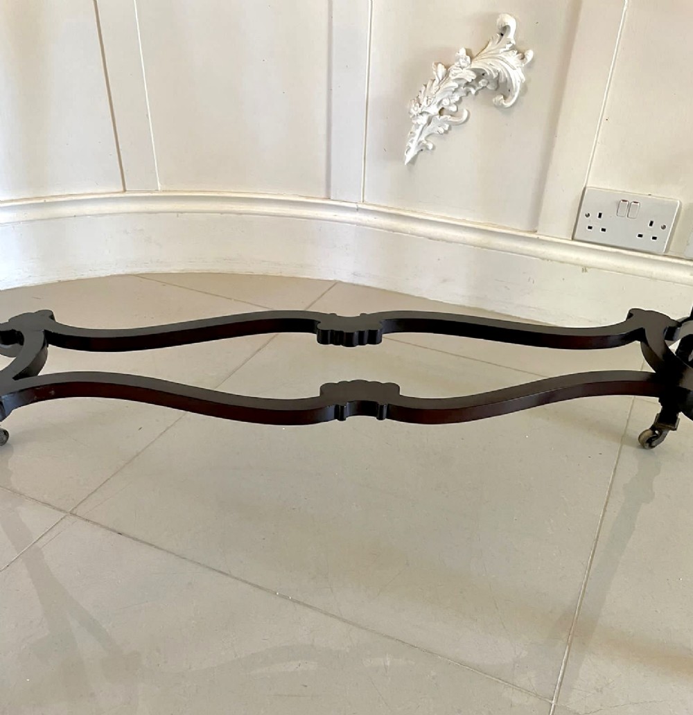 An antique Victorian dark mahogany centre table featuring a shaped serpentine top, carved frieze with brass handles, cabriole legs, and an arched scroll stretcher. View VIII