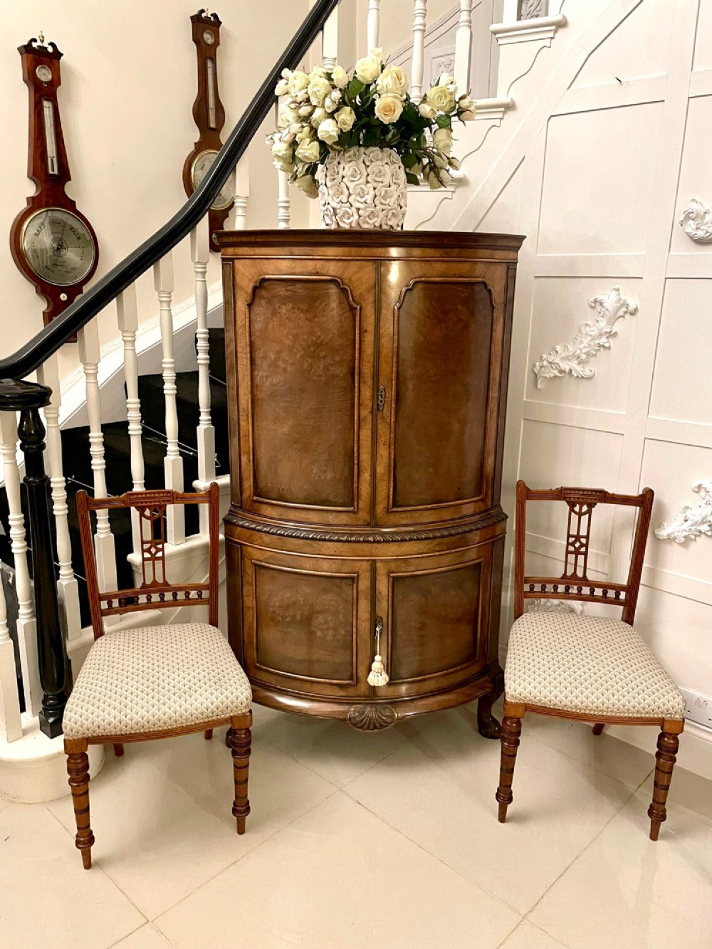 An antique burr walnut bow-fronted cocktail cabinet featuring two upper doors, two lower doors, carved cabriole legs, and brass keyhole escutcheons. View II