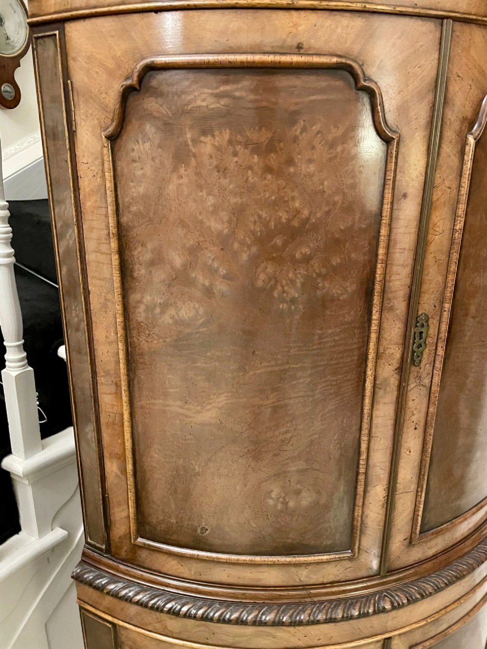 An antique burr walnut bow-fronted cocktail cabinet featuring two upper doors, two lower doors, carved cabriole legs, and brass keyhole escutcheons. View IV