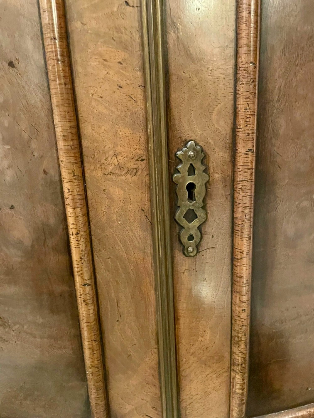 An antique burr walnut bow-fronted cocktail cabinet featuring two upper doors, two lower doors, carved cabriole legs, and brass keyhole escutcheons. View VI