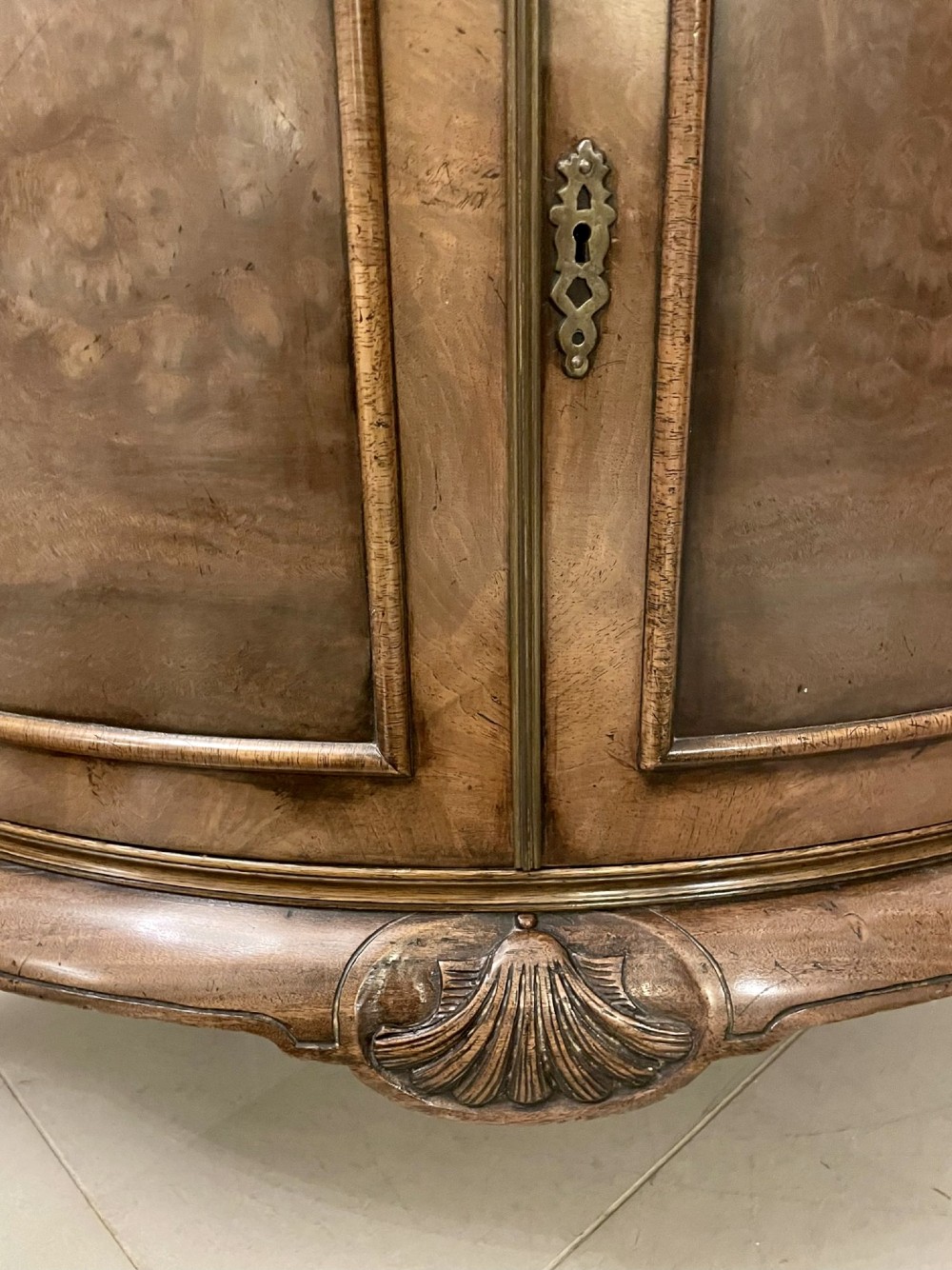 An antique burr walnut bow-fronted cocktail cabinet featuring two upper doors, two lower doors, carved cabriole legs, and brass keyhole escutcheons. View VII