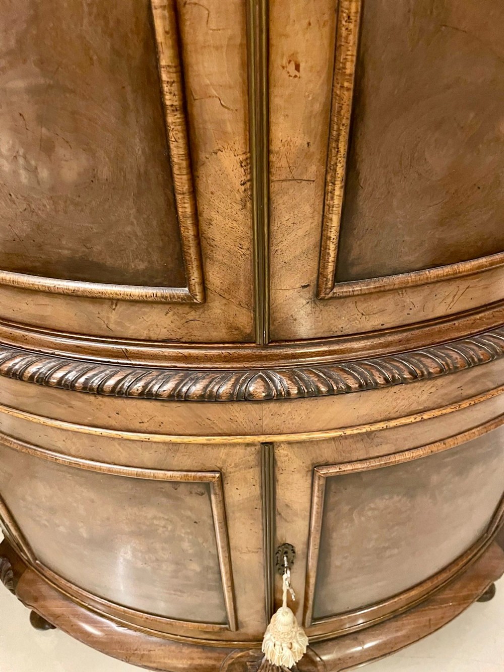 An antique burr walnut bow-fronted cocktail cabinet featuring two upper doors, two lower doors, carved cabriole legs, and brass keyhole escutcheons. View VIII