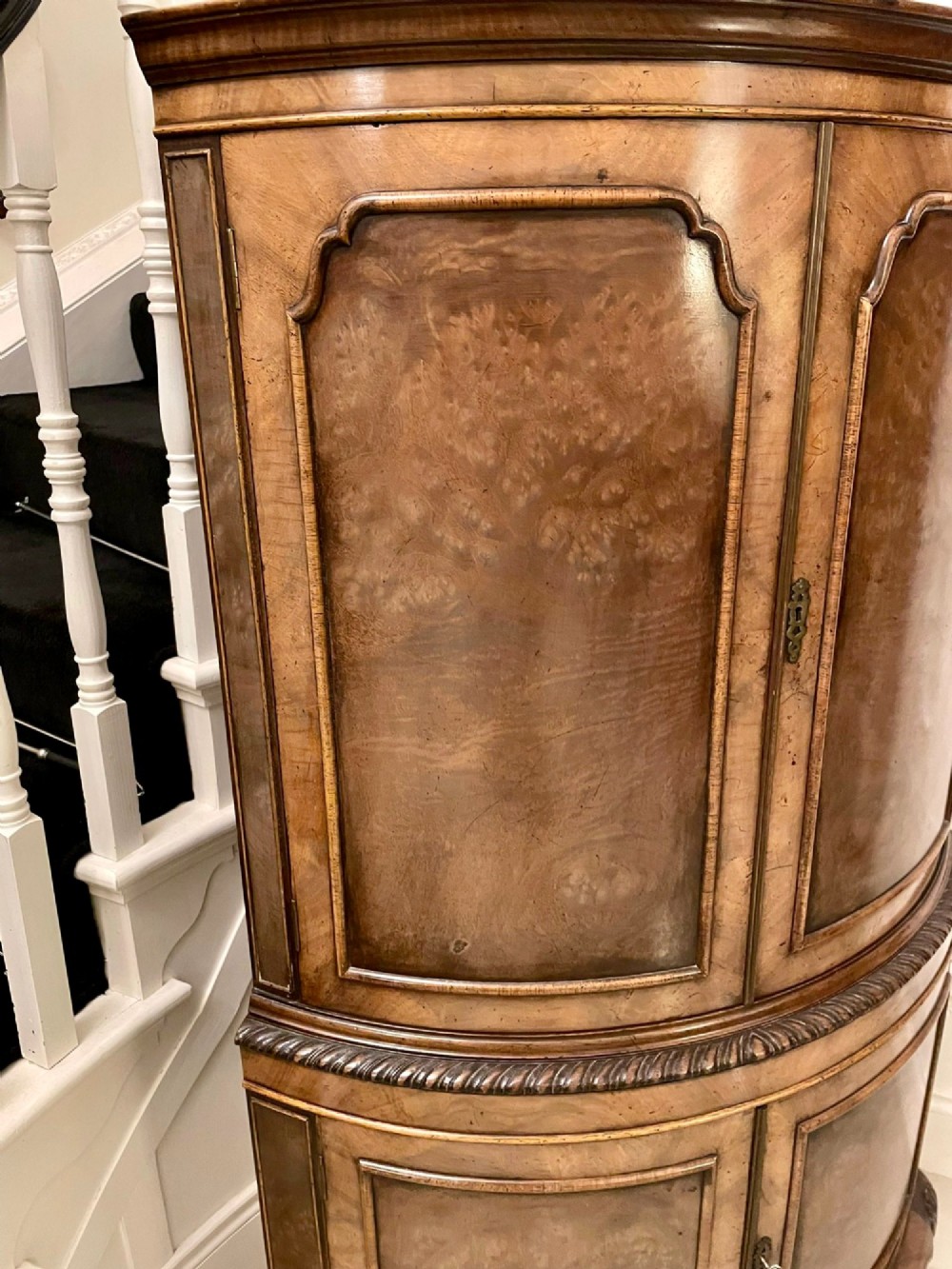 An antique burr walnut bow-fronted cocktail cabinet featuring two upper doors, two lower doors, carved cabriole legs, and brass keyhole escutcheons. View XIII