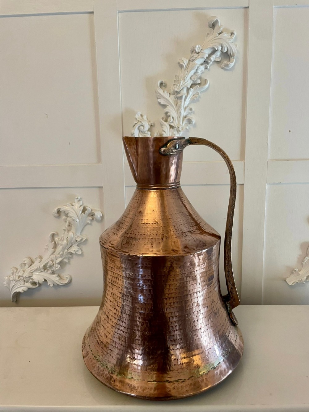 A large George III hand-hammered copper water jug featuring a flared base, narrow neck, and riveted strap handle.