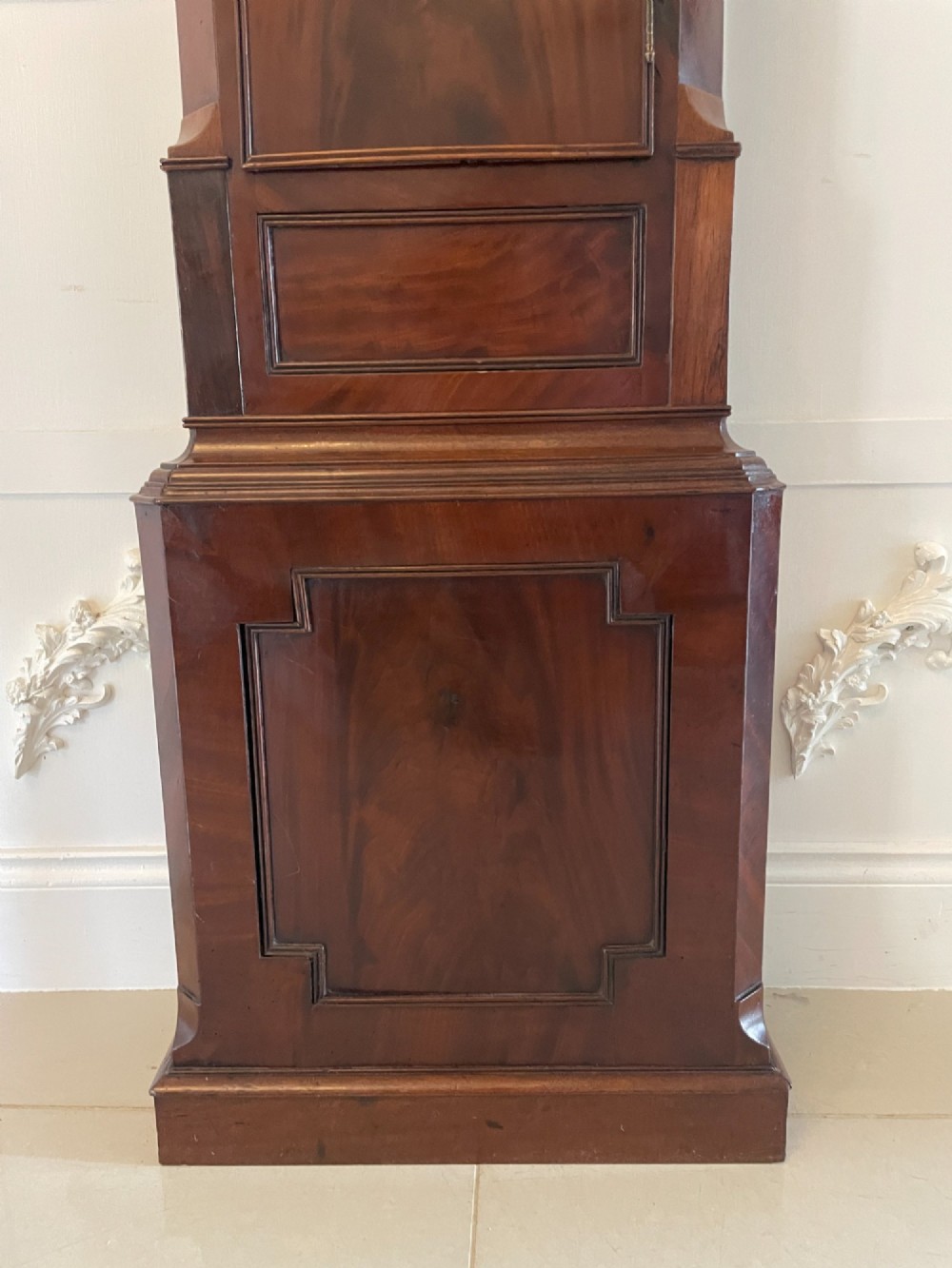 A George III flame mahogany longcase clock featuring a swan-neck pediment, turned hood columns, a painted arch dial, and a gothic-arched trunk door. View IV