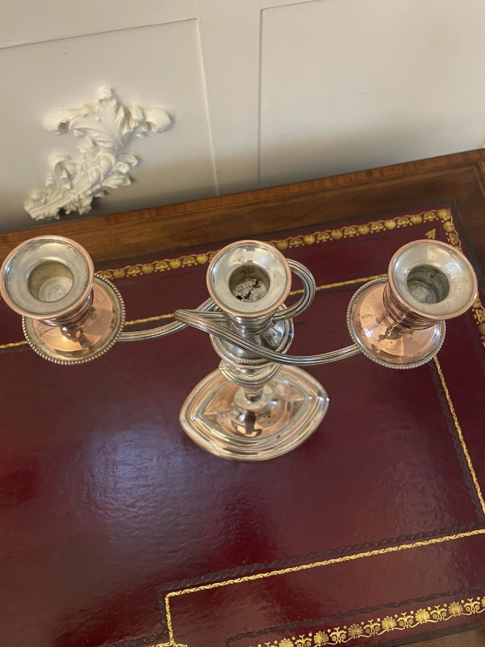 A pair of antique silver-plated three-light candelabras with curved branch arms, tapered baluster stems, and moulded oval bases showing subtle copper undertones. View IV