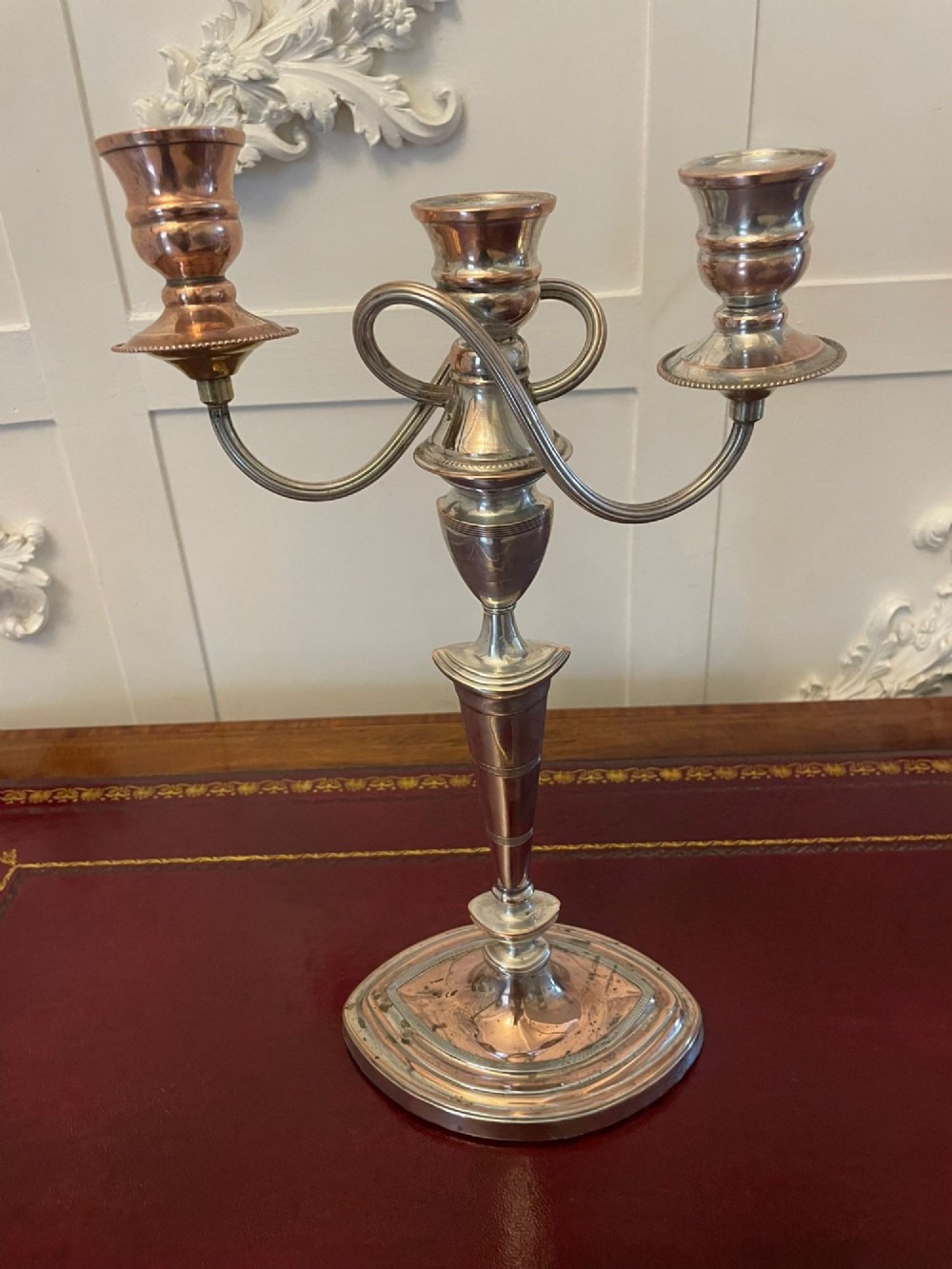 A pair of antique silver-plated three-light candelabras with curved branch arms, tapered baluster stems, and moulded oval bases showing subtle copper undertones. View VI