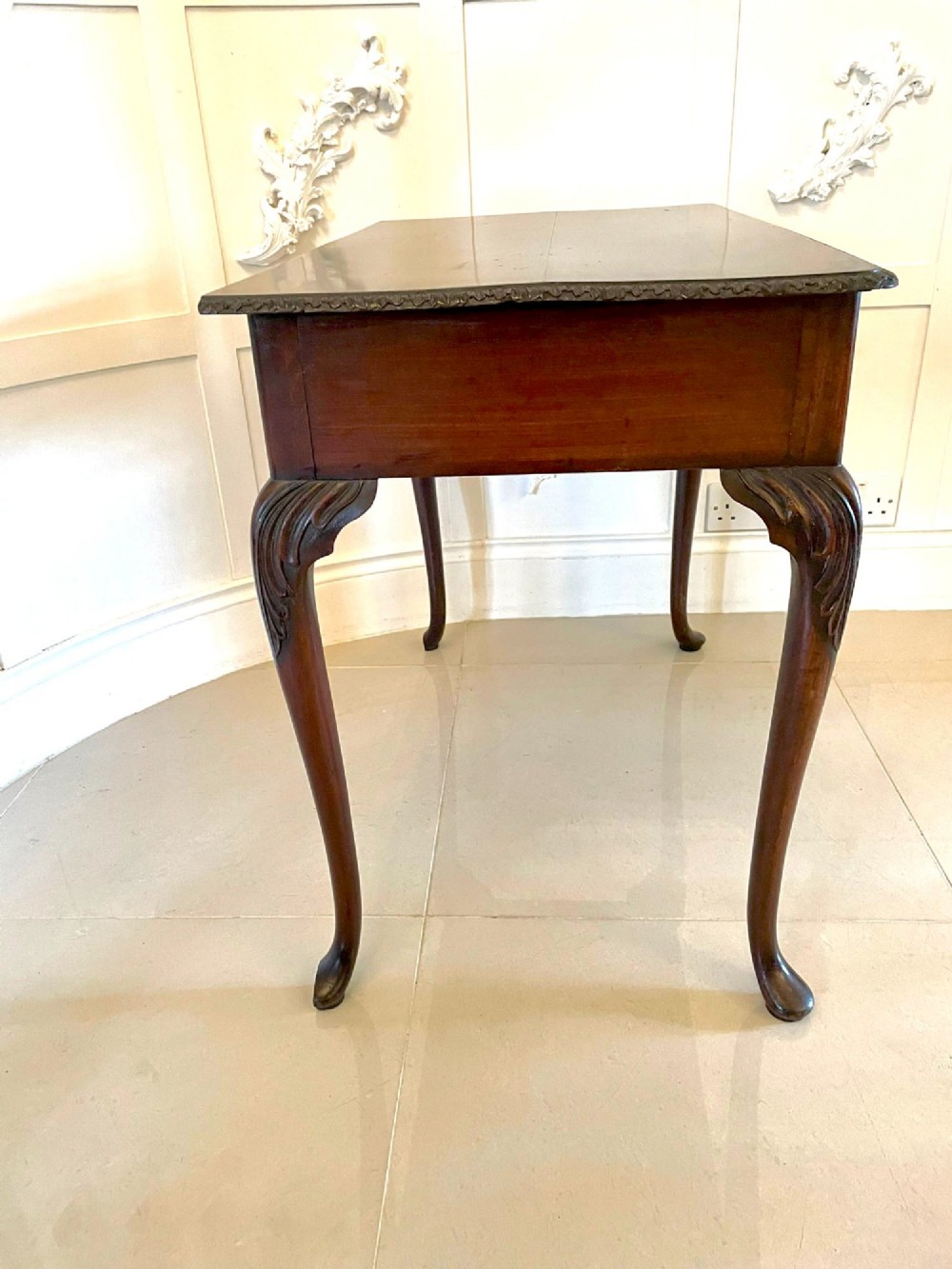 A George III mahogany side table featuring a rectangular top with carved moulding, a long drawer with brass handles, and cabriole legs. View XII