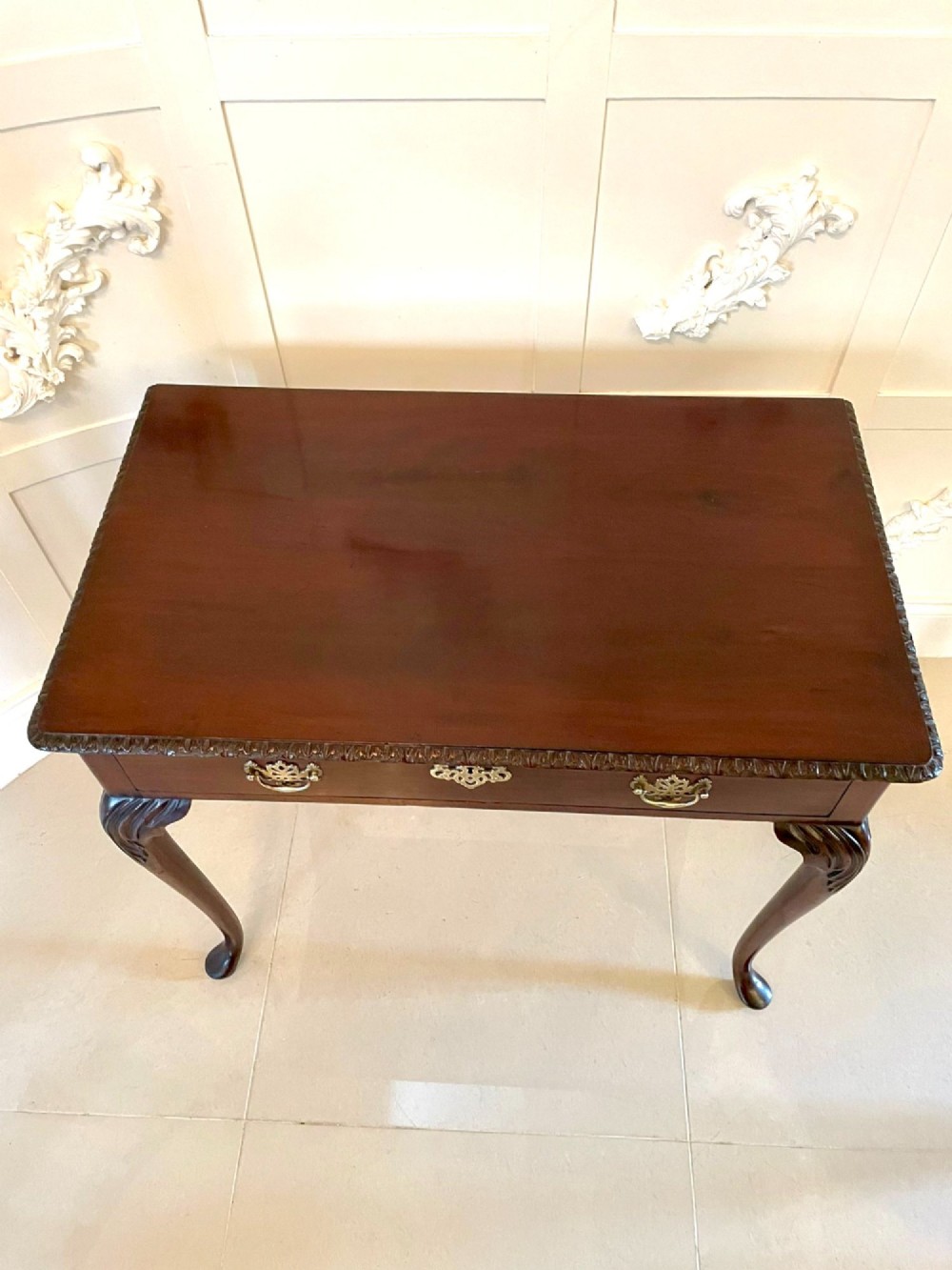 A George III mahogany side table featuring a rectangular top with carved moulding, a long drawer with brass handles, and cabriole legs. View XIII