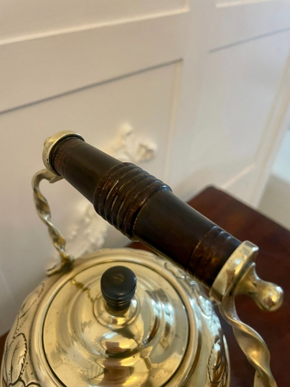 An antique Victorian brass spirit kettle featuring floral engravings, an ebonised wooden handle, and a matching brass stand with a spirit burner. View II
