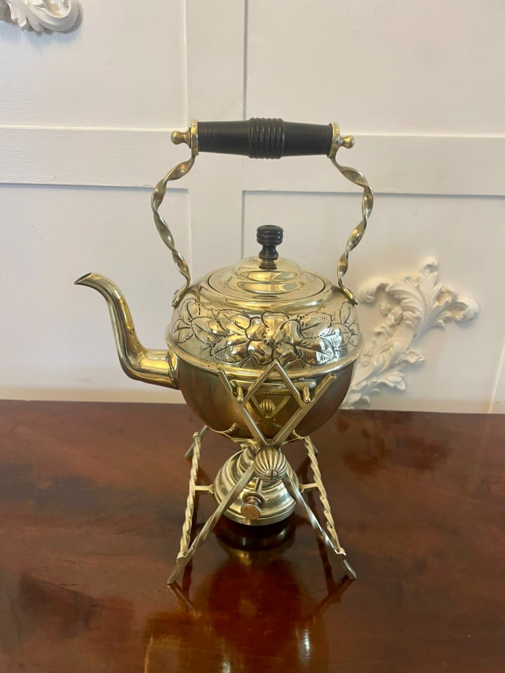 An antique Victorian brass spirit kettle featuring floral engravings, an ebonised wooden handle, and a matching brass stand with a spirit burner. View VII