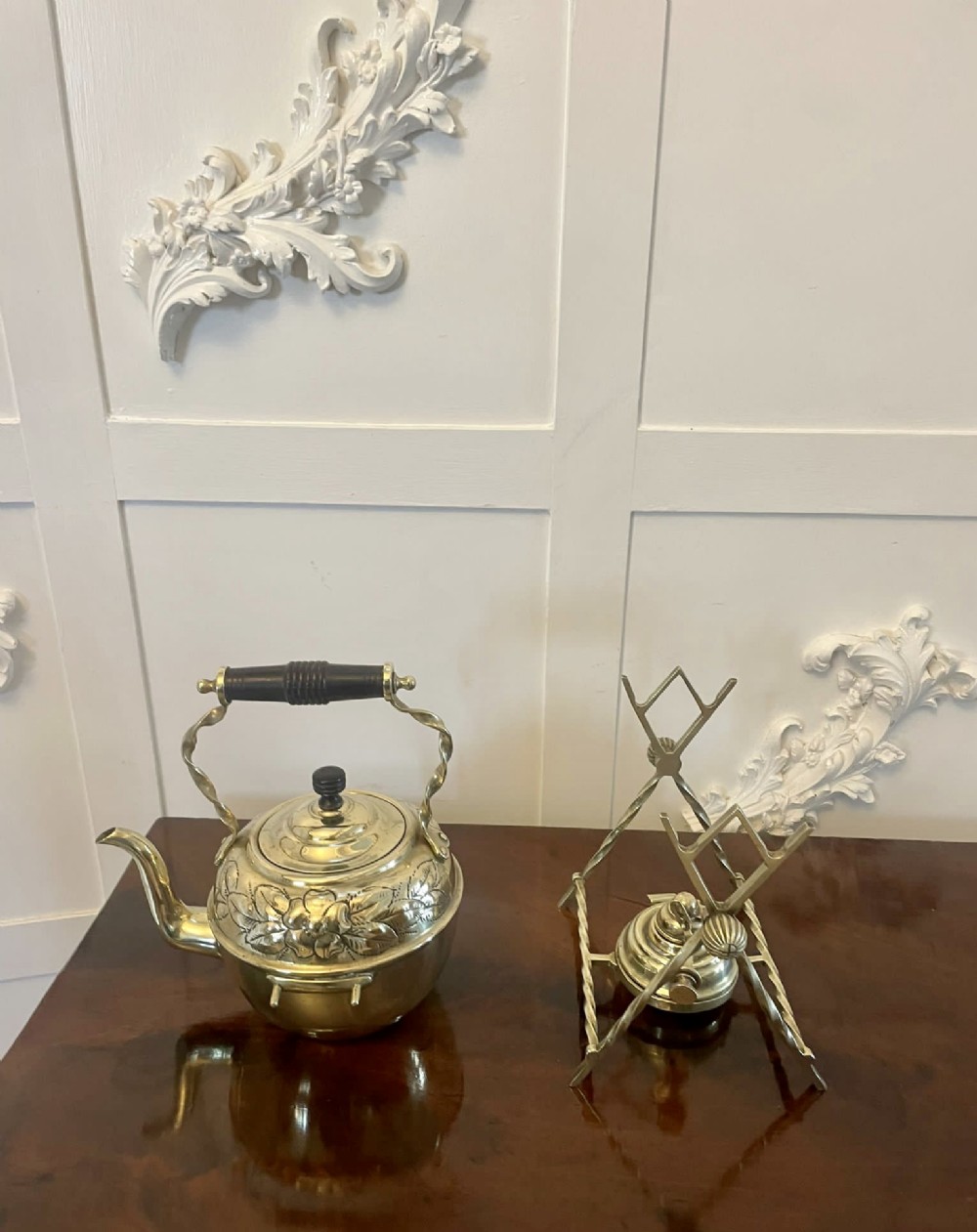 An antique Victorian brass spirit kettle featuring floral engravings, an ebonised wooden handle, and a matching brass stand with a spirit burner. View VIII