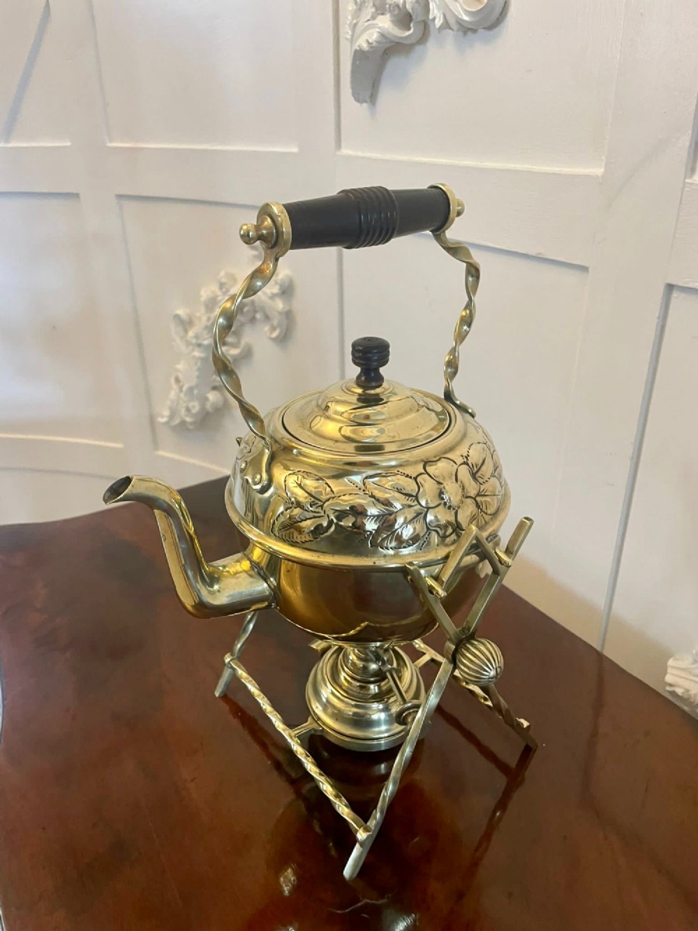 An antique Victorian brass spirit kettle featuring floral engravings, an ebonised wooden handle, and a matching brass stand with a spirit burner. View XI