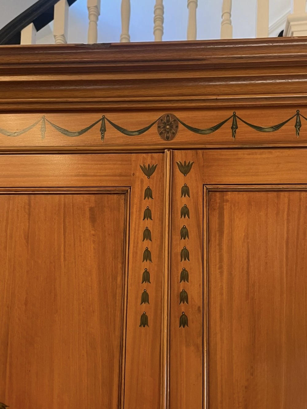 A large satinwood breakfront bookcase featuring hand-painted floral cartouches, upper glazed display doors, and lower cupboard panels. View XI