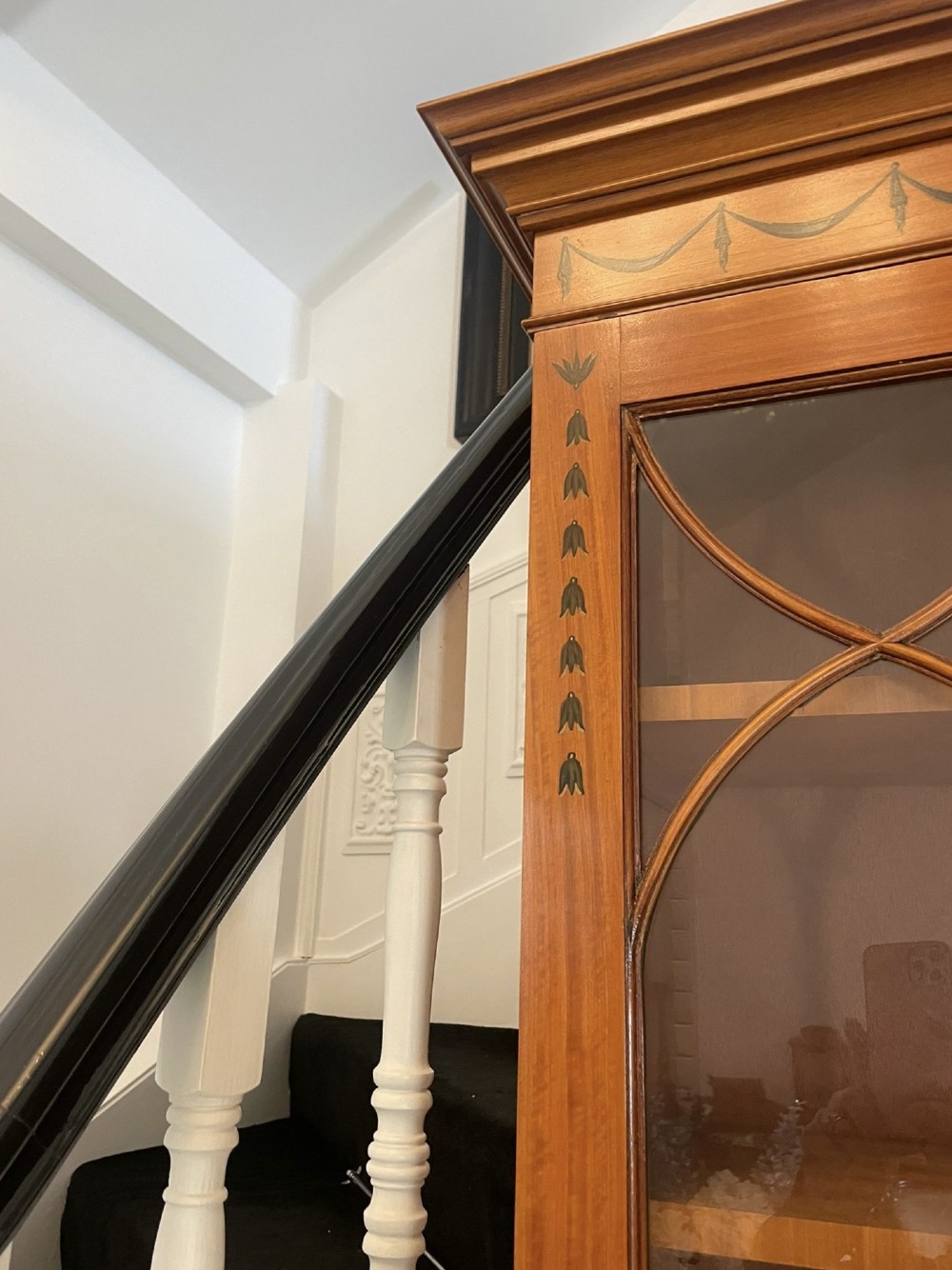 A large satinwood breakfront bookcase featuring hand-painted floral cartouches, upper glazed display doors, and lower cupboard panels. View XIV