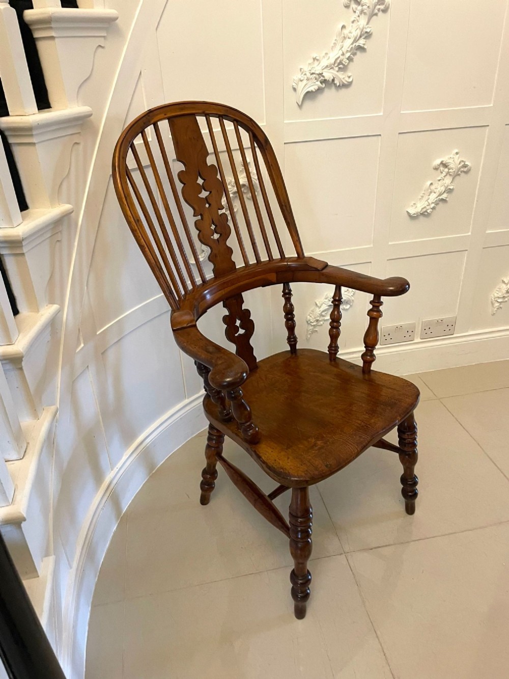 An antique Victorian yew wood Windsor armchair featuring a hoop back, spindle backrest with a central pierced splat, broad arms, and turned legs.