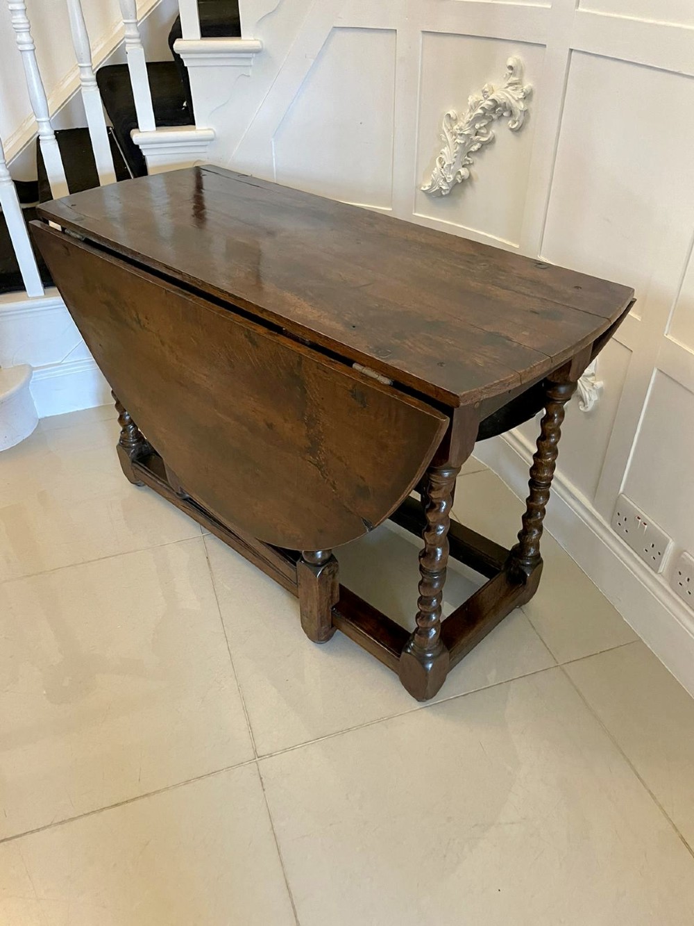 A dark oak seventeenth-century gateleg dining table with folded drop leaves, barley twist legs, and sturdy base stretchers. View V