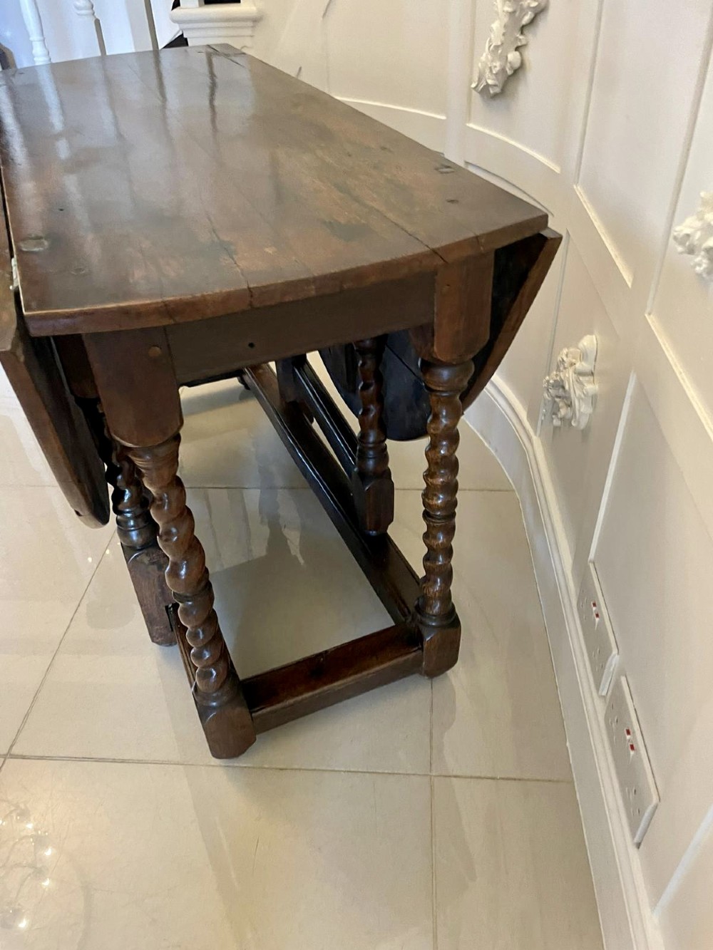 A dark oak seventeenth-century gateleg dining table with folded drop leaves, barley twist legs, and sturdy base stretchers. View X