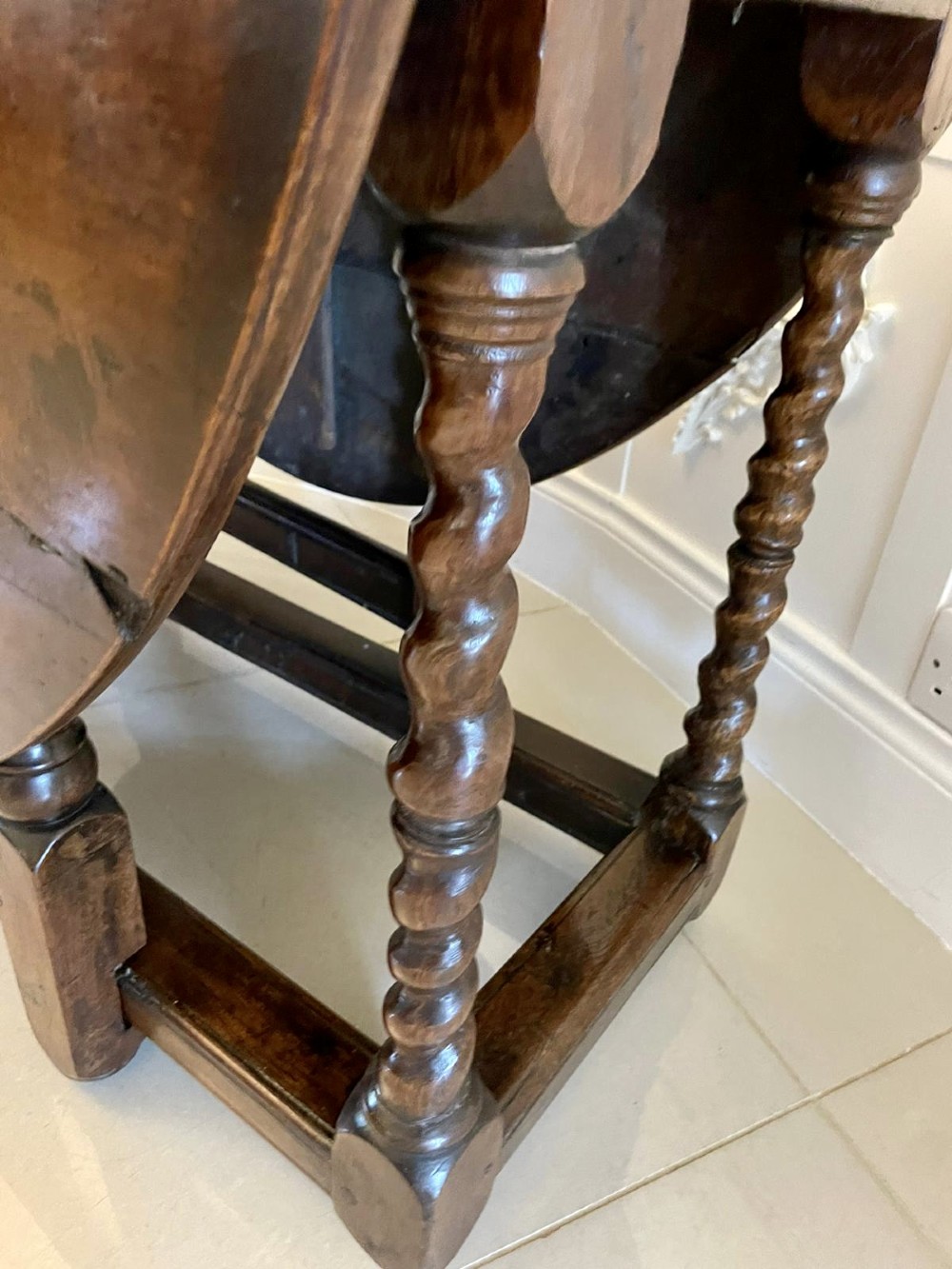 A dark oak seventeenth-century gateleg dining table with folded drop leaves, barley twist legs, and sturdy base stretchers. View XII