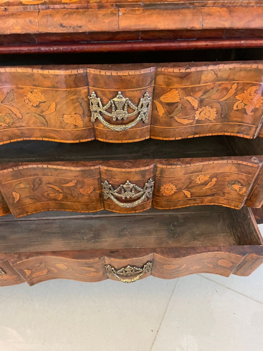 An antique Dutch burr walnut display cabinet featuring elaborate floral marquetry inlay, glazed upper doors, a serpentine three-drawer base, and carved claw feet. View VIII
