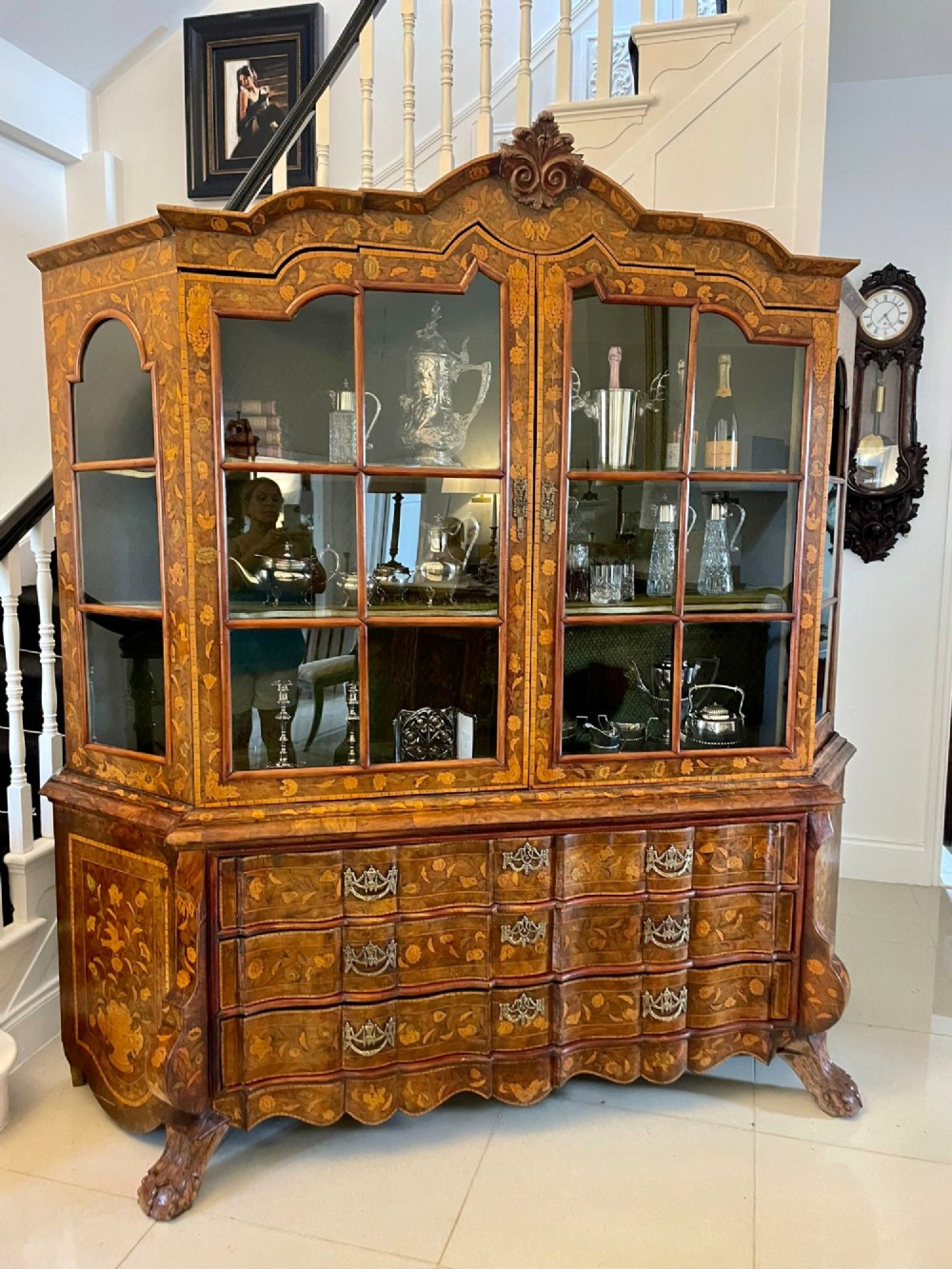 An antique Dutch burr walnut display cabinet featuring elaborate floral marquetry inlay, glazed upper doors, a serpentine three-drawer base, and carved claw feet. View XV