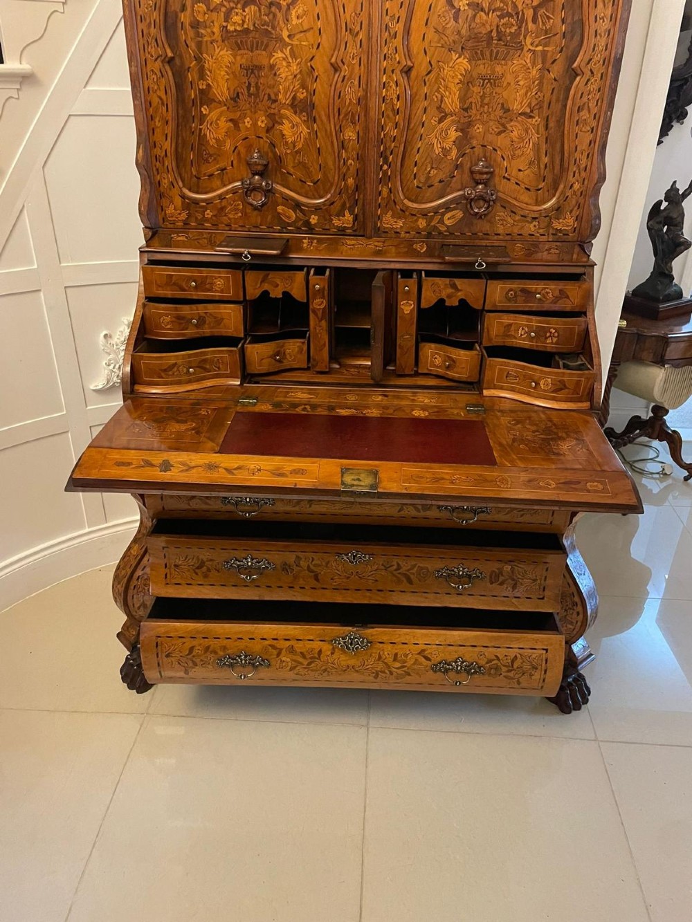 An 18th-century Dutch burr walnut bureau bookcase featuring intricate floral marquetry, a bombe lower drawer section, a fall-front desk slope, and an arched twin-door upper cabinet supported on claw feet. View V