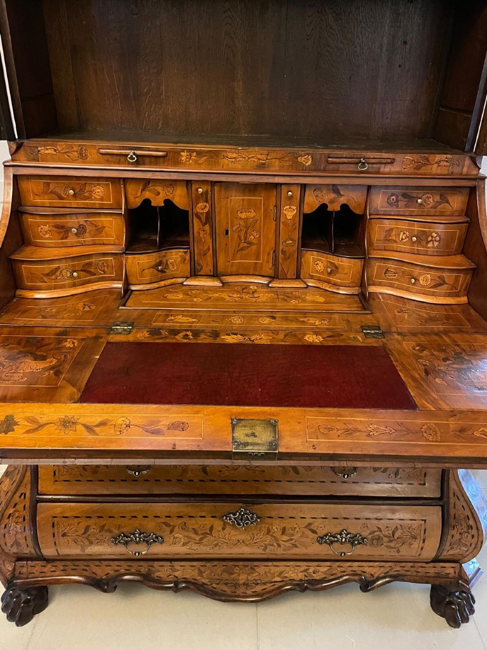 An 18th-century Dutch burr walnut bureau bookcase featuring intricate floral marquetry, a bombe lower drawer section, a fall-front desk slope, and an arched twin-door upper cabinet supported on claw feet. View VI