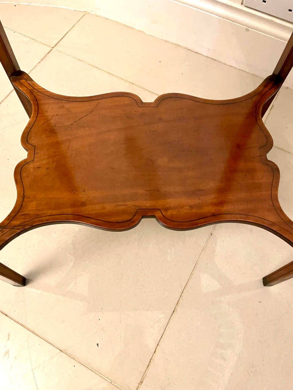An Edwardian rectangular satinwood inlaid side table featuring a raised tray top with central musical instrument marquetry, slender square tapered legs, and a shaped undertier shelf. View II