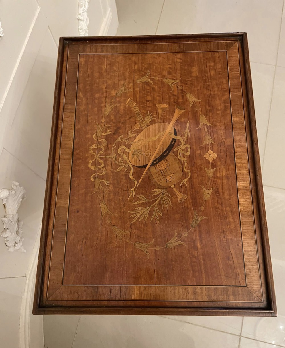 An Edwardian rectangular satinwood inlaid side table featuring a raised tray top with central musical instrument marquetry, slender square tapered legs, and a shaped undertier shelf. View VI