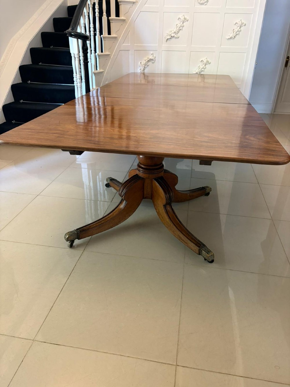 A large George III figured mahogany twin-pillar extending dining table with splayed tripod legs ending in brass castors. View V