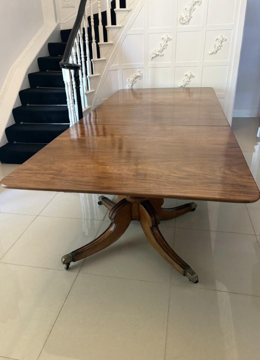 A large George III figured mahogany twin-pillar extending dining table with splayed tripod legs ending in brass castors. View VIII
