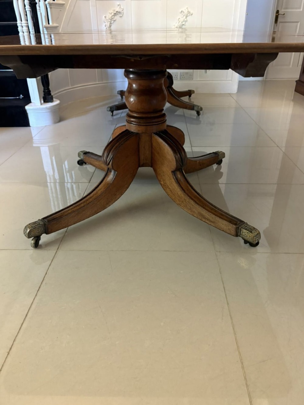 A large George III figured mahogany twin-pillar extending dining table with splayed tripod legs ending in brass castors. View X