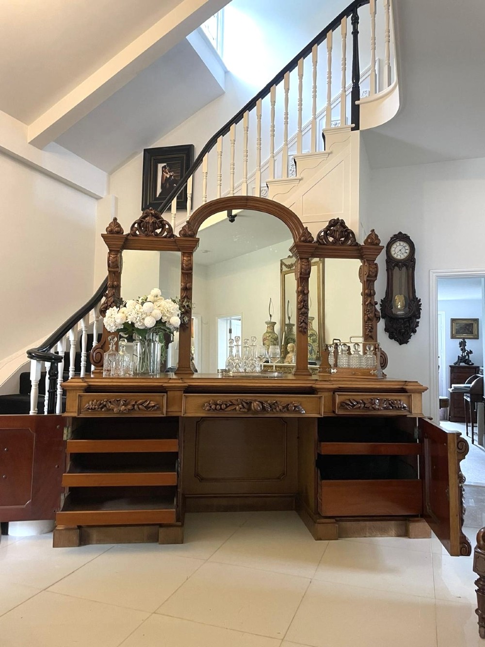 A large Victorian carved oak sideboard featuring three upper mirror panels, intricate grape cluster wood carvings, and a pedestal base. View II