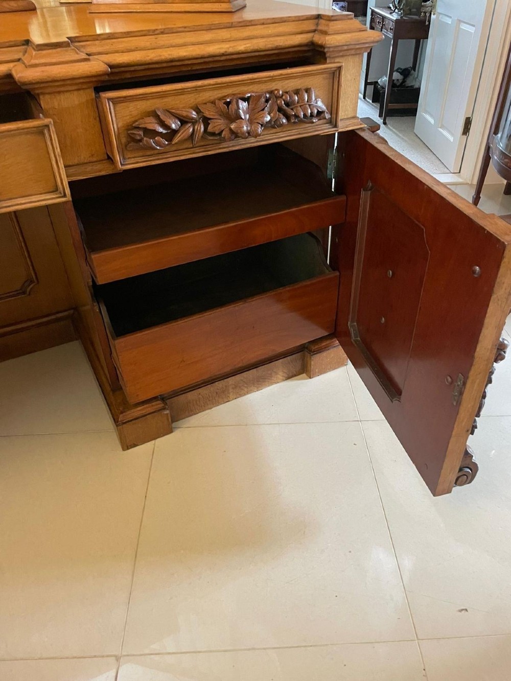 A large Victorian carved oak sideboard featuring three upper mirror panels, intricate grape cluster wood carvings, and a pedestal base. View III