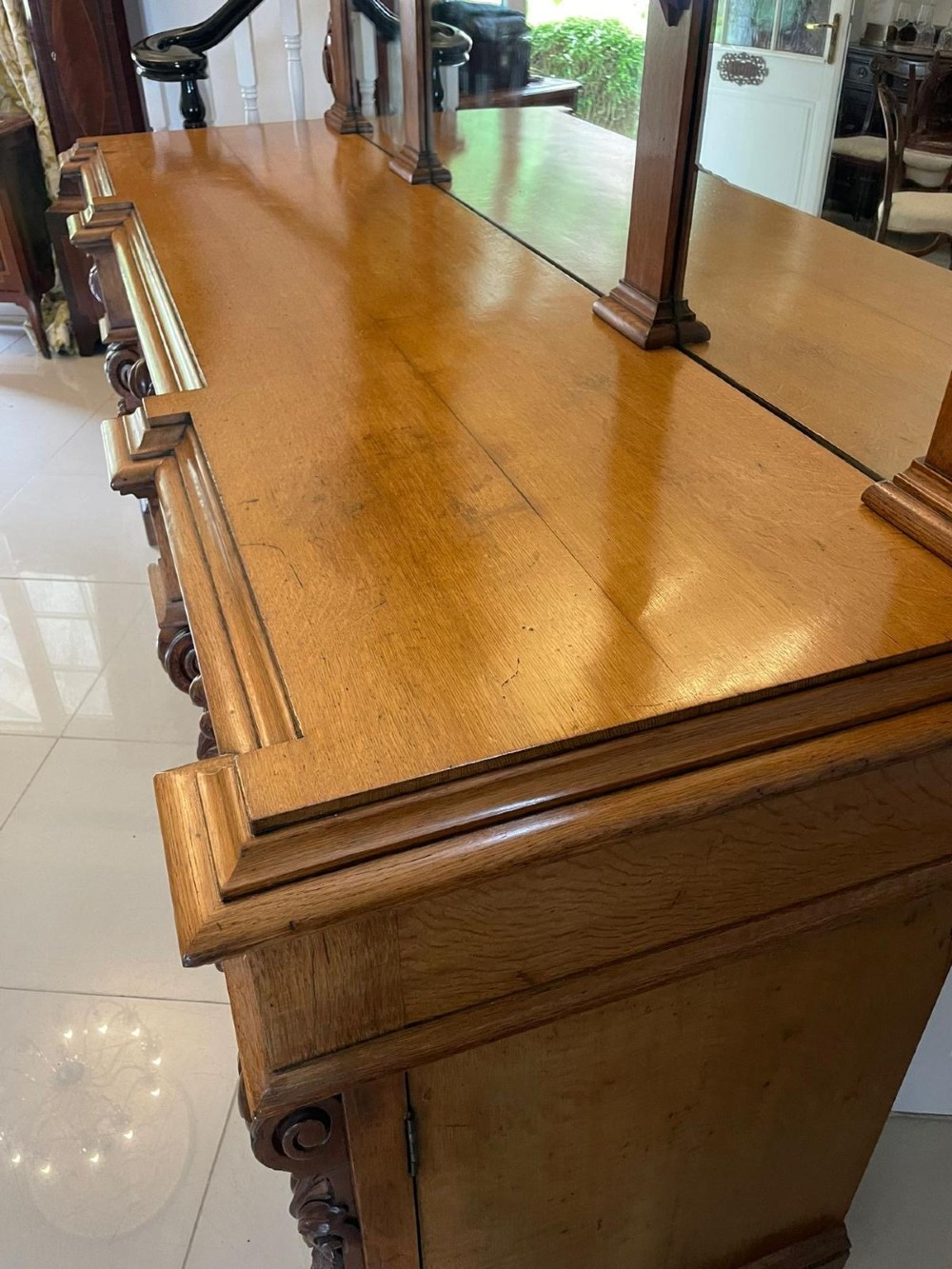 A large Victorian carved oak sideboard featuring three upper mirror panels, intricate grape cluster wood carvings, and a pedestal base. View X