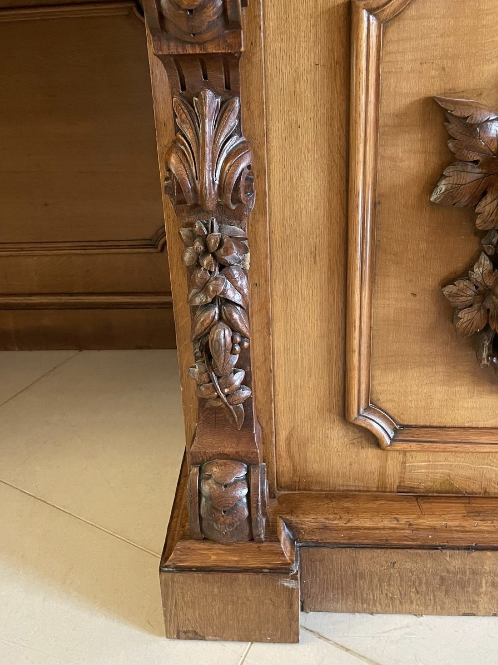 A large Victorian carved oak sideboard featuring three upper mirror panels, intricate grape cluster wood carvings, and a pedestal base. View XIV