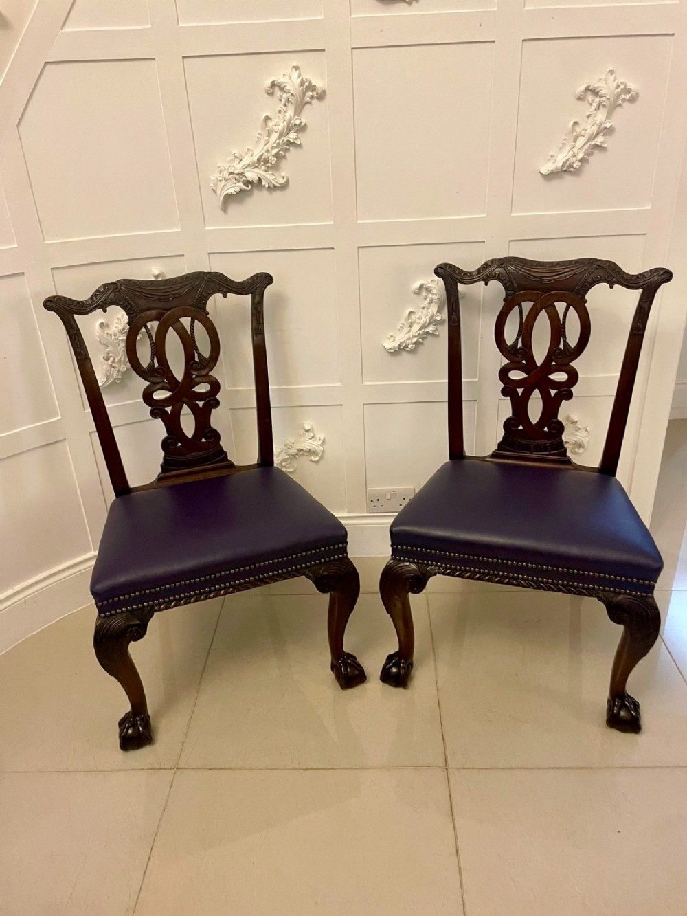 A set of carved mahogany dining chairs featuring pierced back splats, ball and claw feet, and purple leather seats. View XV