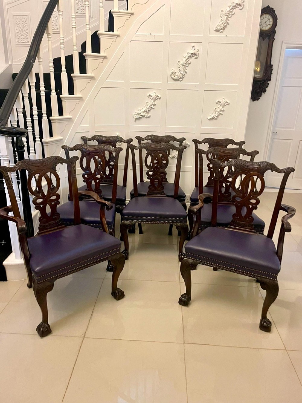 A set of carved mahogany dining chairs featuring pierced back splats, ball and claw feet, and purple leather seats.