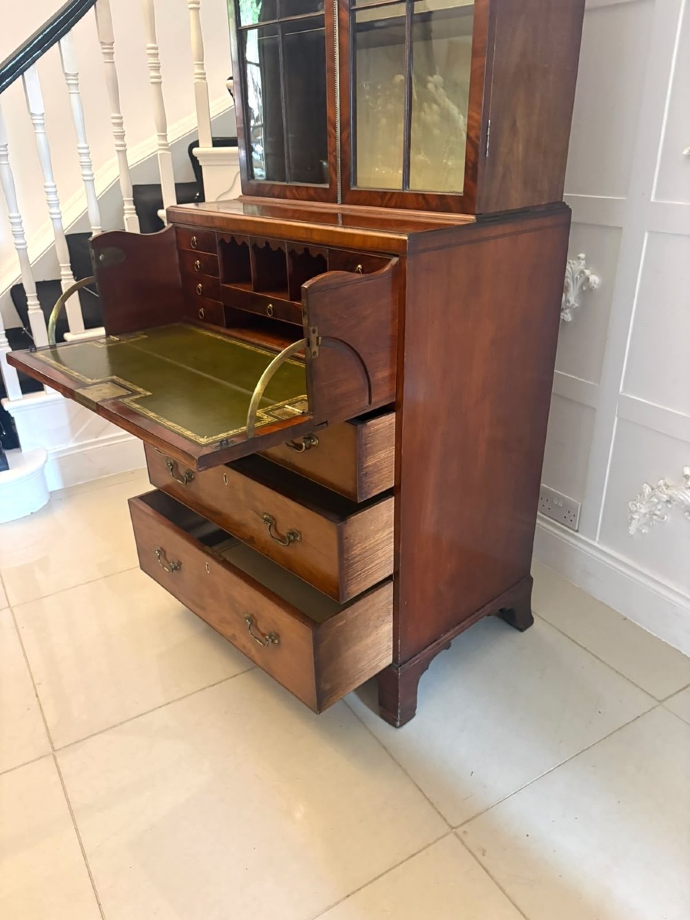 A tall Georgian mahogany secretaire bookcase featuring an upper cabinet with astragal glazed doors and a lower chest of drawers with brass handles. View X
