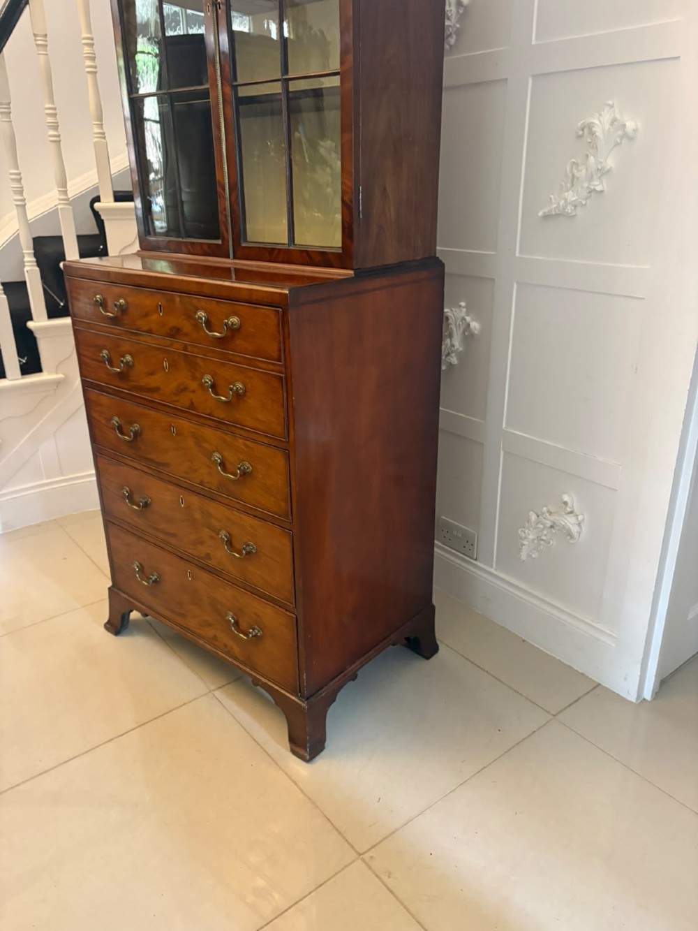 A tall Georgian mahogany secretaire bookcase featuring an upper cabinet with astragal glazed doors and a lower chest of drawers with brass handles. View XV