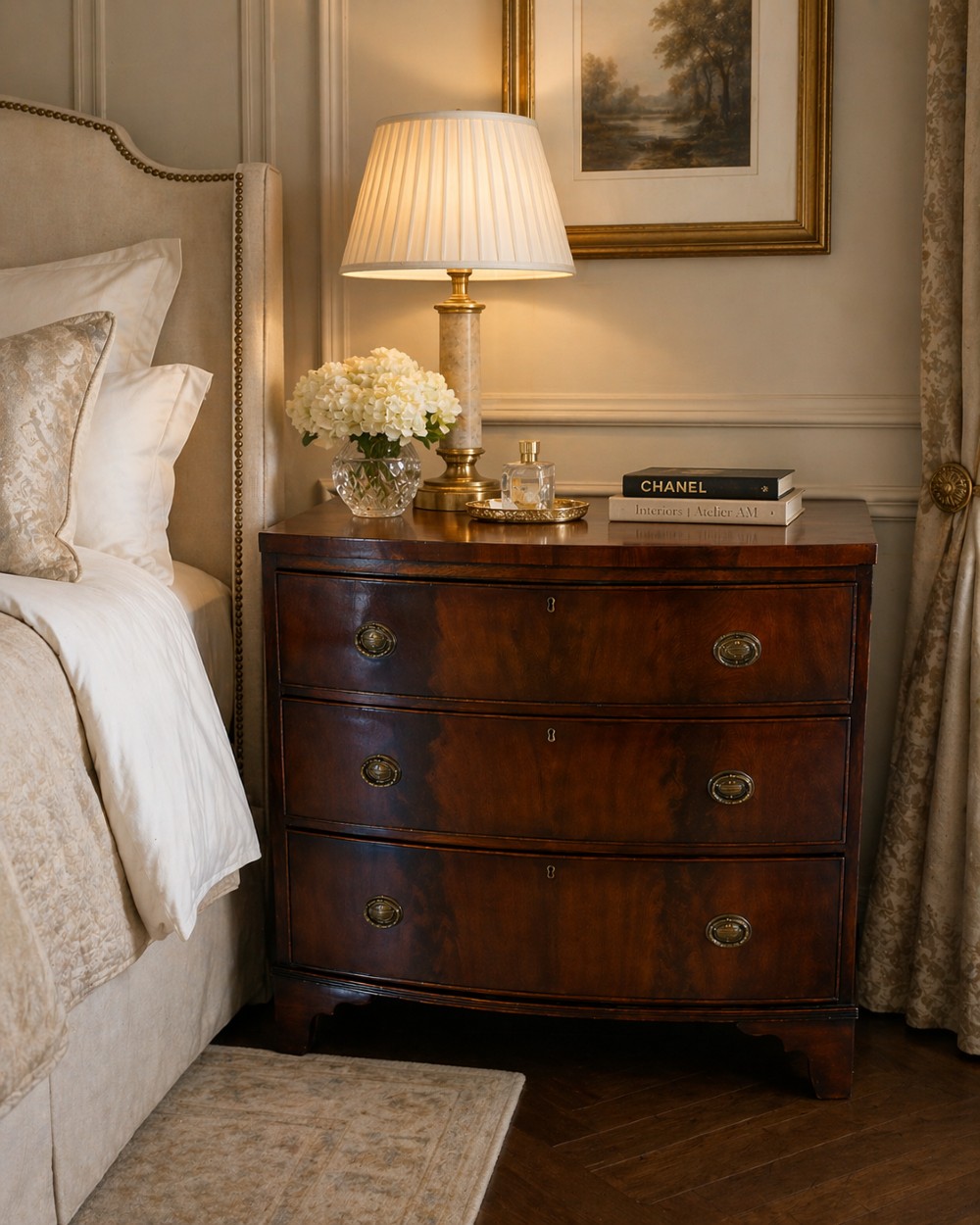A Georgian mahogany bow-front chest of three drawers featuring oval brass drop handles and raised on bracket feet. View V