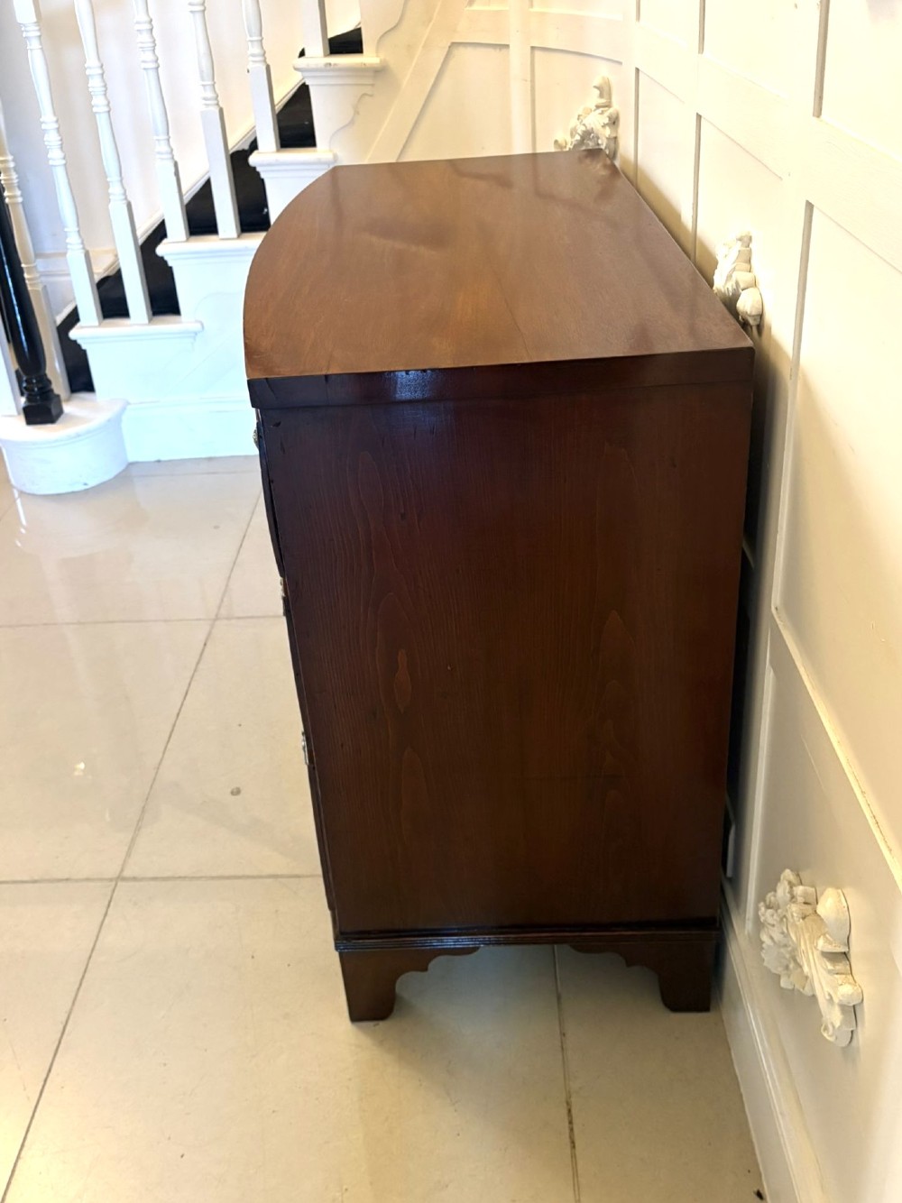 A Georgian mahogany bow-front chest of three drawers featuring oval brass drop handles and raised on bracket feet. View XI