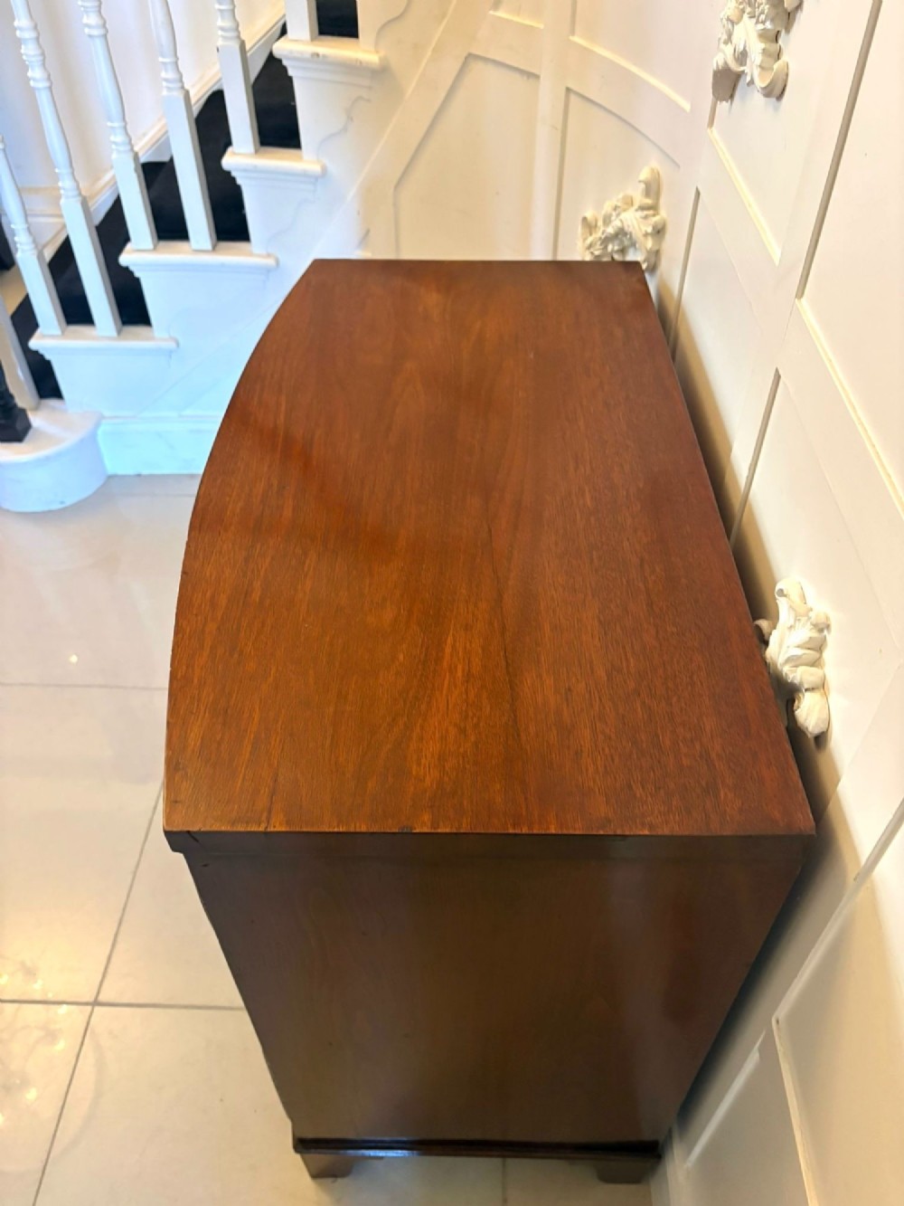 A Georgian mahogany bow-front chest of three drawers featuring oval brass drop handles and raised on bracket feet. View XII