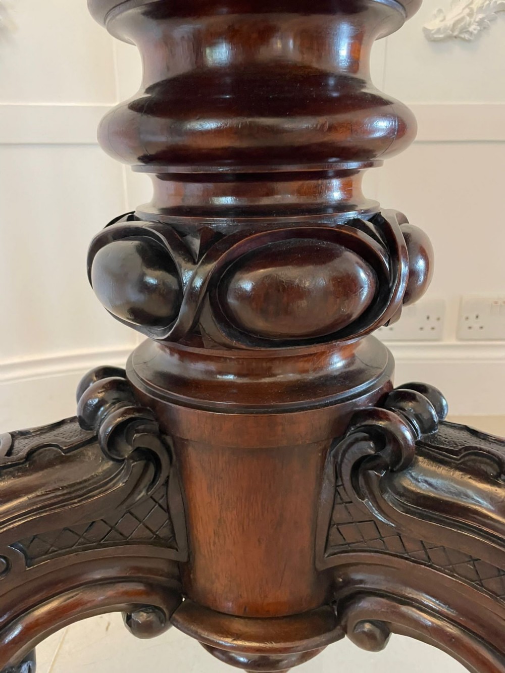 An Early Victorian octagonal rosewood centre table shown tilted upright to display its flame-figured grain and carved pedestal base with scrolled feet. View VII